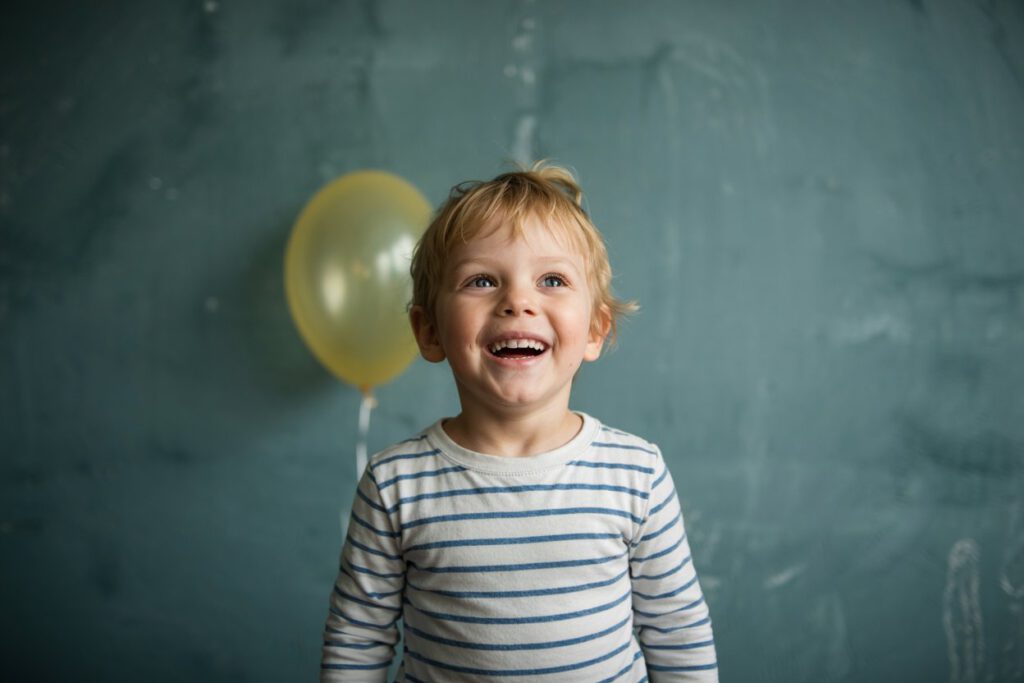 Lächelnder Junge vor grünem Hintergrund beim Fototermin mit einem Kindergartenfotografen in Köln