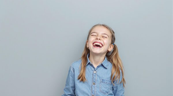 Fröhlich lachendes Mädchen vor grauem Hintergrund beim Fototermin mit einem Kindergartenfotografen in Köln